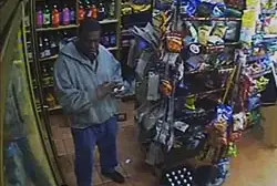 Surveillance video still of the rape suspect using the victim's ATM card at a bodega